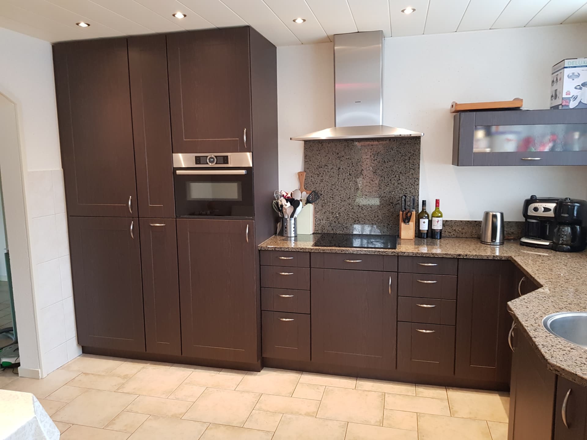 Hoekkeuken in donkerbruine houtlook met stenen werkblad
