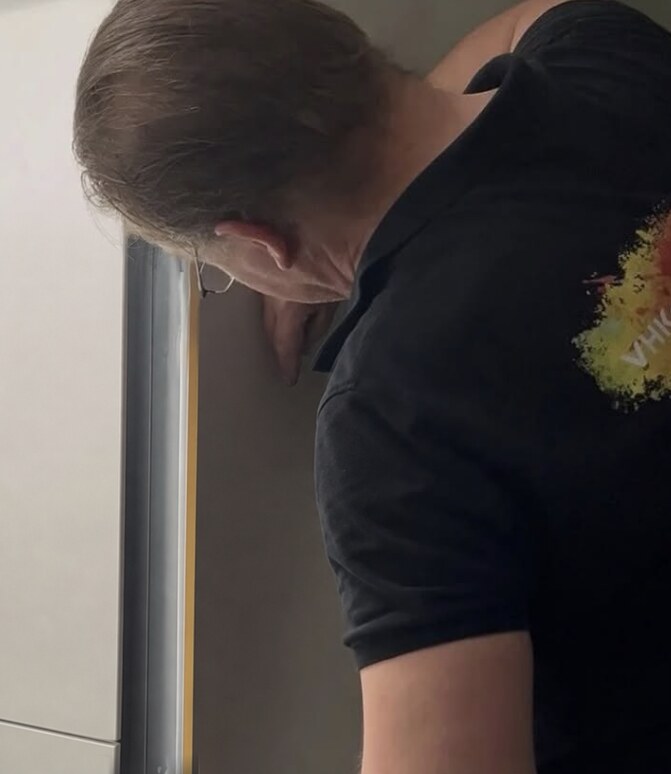 Patrick brengt folie aan op een keukenkastje